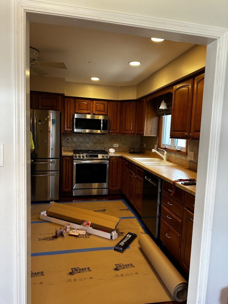 A kitchen in the early stages of a remodel, with floor protection and new material boxes, managed by Keeler Construction Group Inc. in Blue Island, IL.