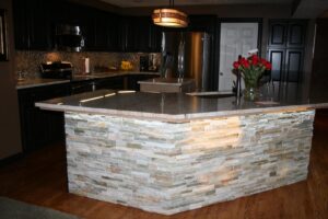 A beautifully remodeled kitchen featuring a stone-faced island and dark cabinets by Handyman Joe in Omaha, NE