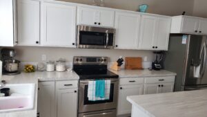 A completed kitchen remodel with white cabinets and new stainless steel appliances by Constructed by 360 LLC in Meridian, ID.