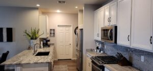 A kitchen remodel featuring white cabinets, granite countertops, and a dark sink by LJ Builders in Chandler, AZ