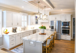 A newly remodeled kitchen featuring white cabinets, a grey island, and stainless steel appliances by Counter Fitters in Savannah, GA
