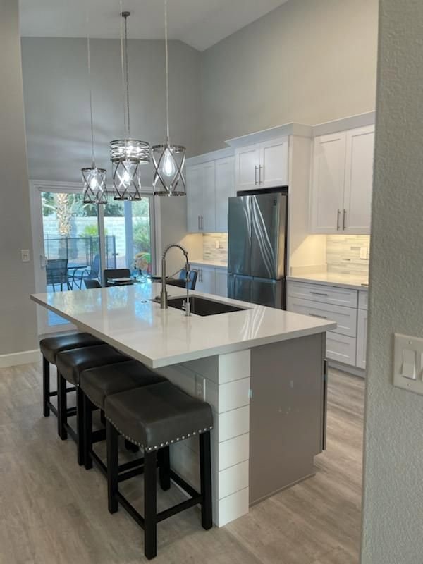 A bright kitchen remodel with white cabinets, a large island, and modern pendant lights by Integrity Contracting in Cleveland, OH