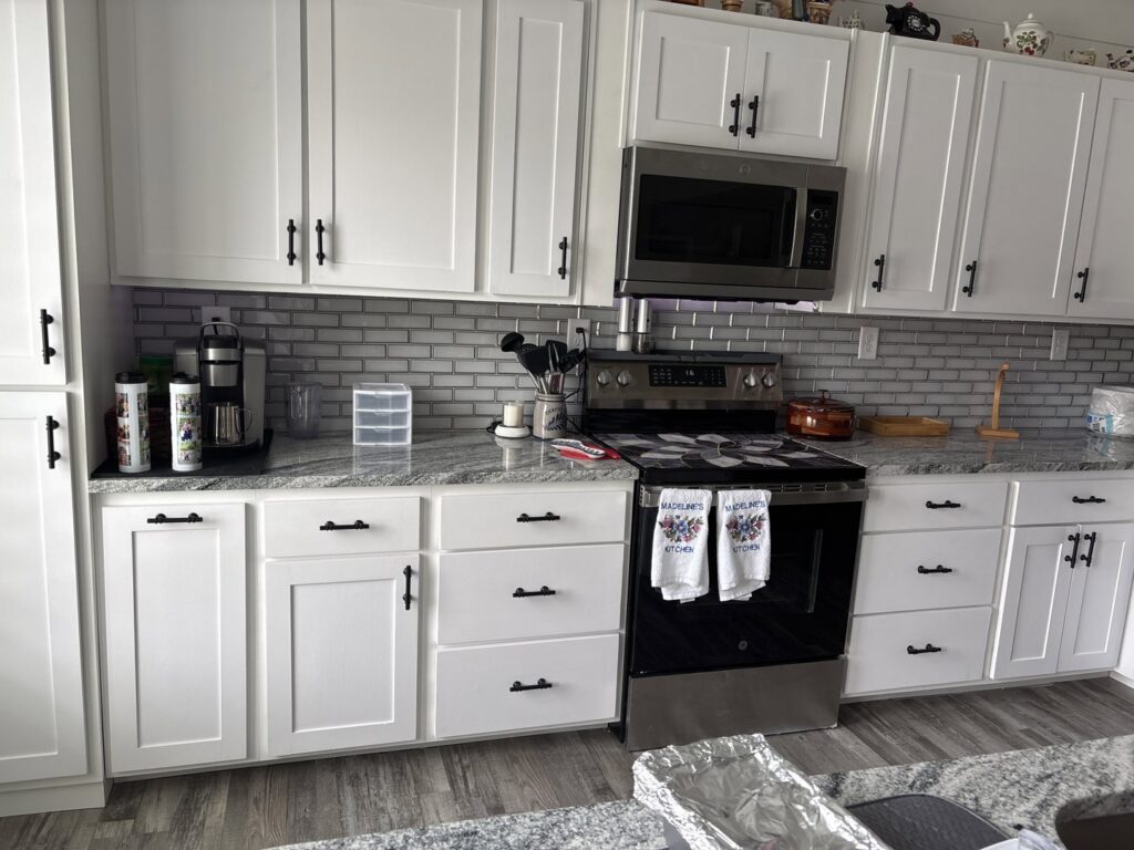 A beautifully remodeled kitchen featuring white shaker cabinets, subway tile backsplash, and granite countertops by KB Home Repairs & Improvements, LLC in Shawnee, KS.