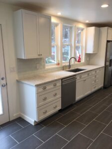 A kitchen remodel showcasing white cabinets, light granite countertops, and a subway tile backsplash by TPF Services in Yakima, WA.