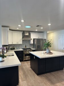 A recently completed kitchen remodel with white upper and dark lower cabinets, and a large island by Integrity Contracting in Cleveland, OH