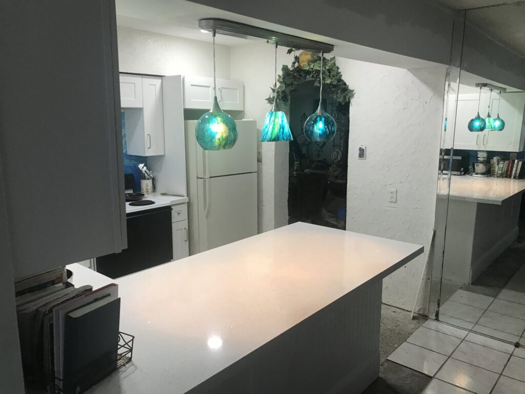 A kitchen remodel featuring an island and white cabinets by BRM Construction in Miami, FL.