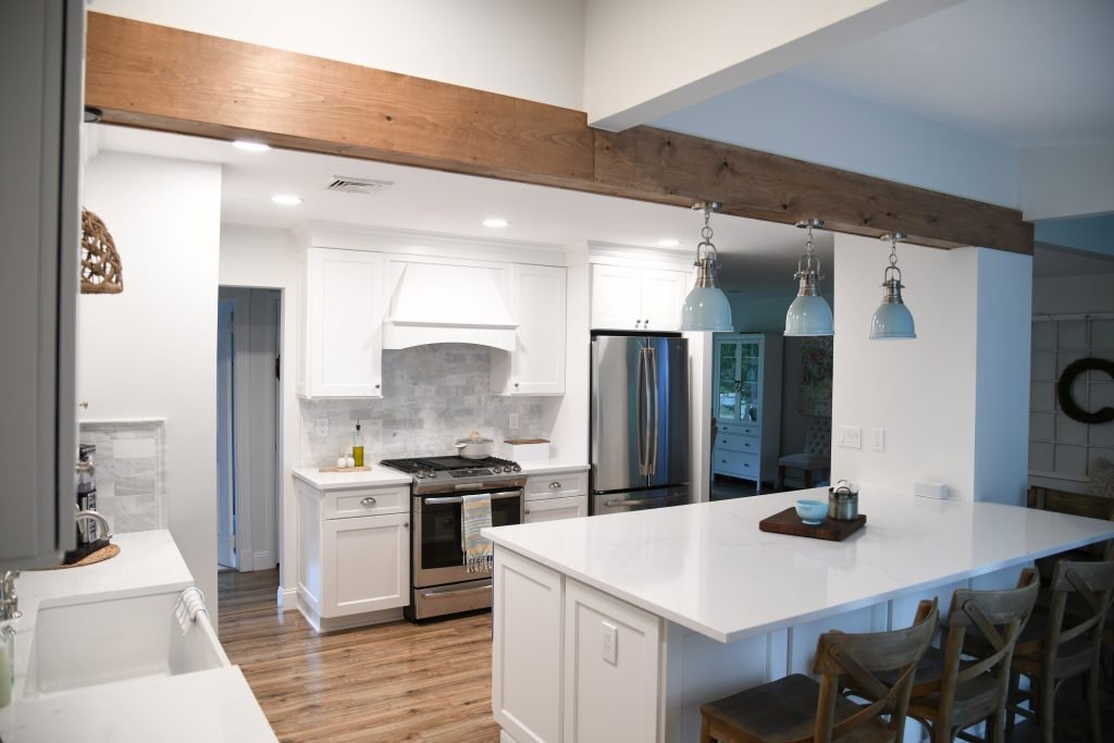 A modern kitchen remodel featuring white cabinets, a large island, and exposed beam by Stanley Contracting in Whiting, NJ