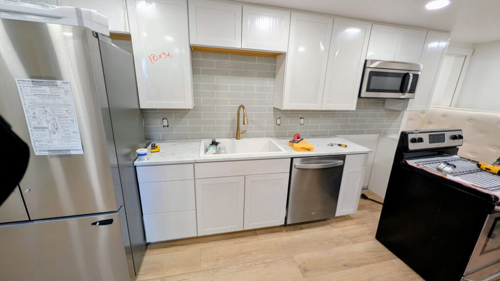 A newly remodeled kitchen with white cabinets, subway tile backsplash, and new appliances by SurePlan Handyman in North Ogden, UT