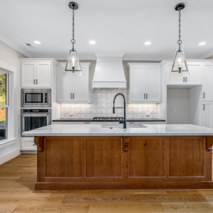 A renovated kitchen featuring white cabinets, a wood island, and new appliances installed by Mitchco, Inc. in Winston-Salem, NC.