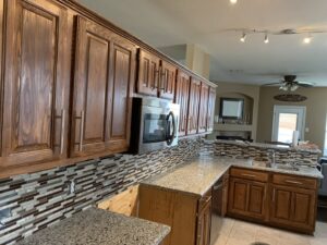 A completed kitchen remodel showcasing wooden cabinets, granite countertops, and a tiled backsplash by Brewer Builds in Fort Worth, TX.