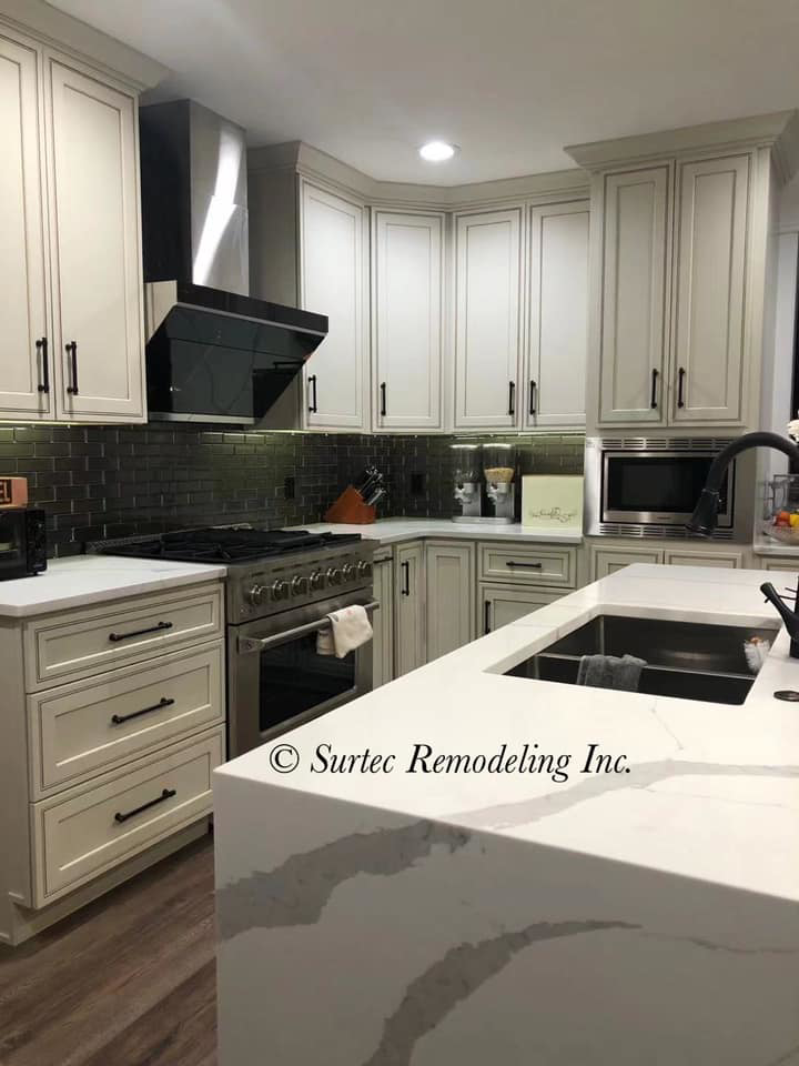 Remodeled kitchen showcasing new appliances, white cabinets, and a spacious island by Surtec Remodeling Inc. in Pittsburgh, PA.