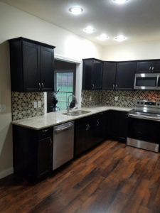 A newly remodeled kitchen with dark cabinets, tiled backsplash, and stainless steel appliances by Waltz Contracting LLC in Bloomington, IN