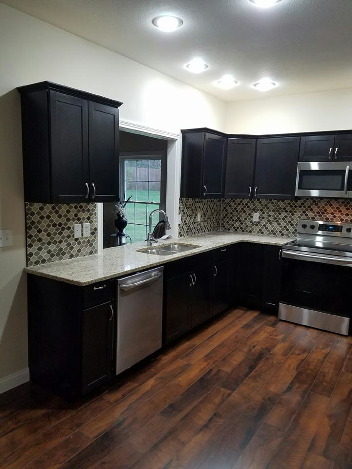 A newly remodeled kitchen with dark cabinets, tiled backsplash, and stainless steel appliances by Waltz Contracting LLC in Bloomington, IN