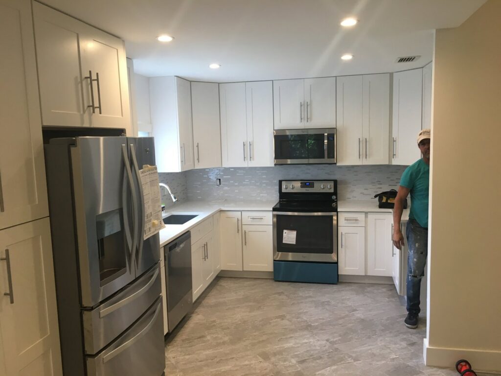 A completed kitchen remodeling project with white cabinets and modern appliances by BRM Construction in Miami, FL.