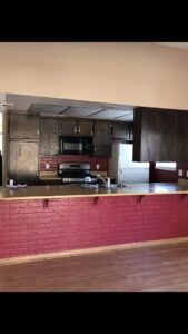 A kitchen with dark cabinets and a red brick-patterned bar, representing a potential renovation project by Mancusi Home Maintenance in Boulder City, NV.