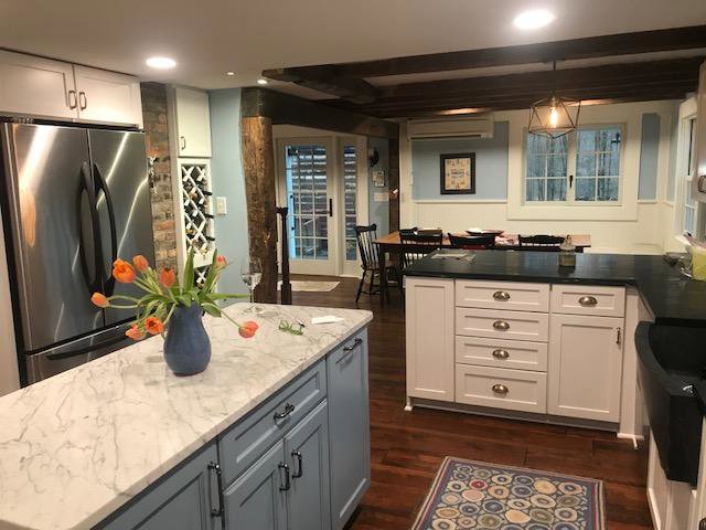 A kitchen renovation showcasing a blue island, marble countertops, and exposed wooden beams by Adam Ross Cut Stone in Albany, NY.