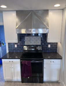 A kitchen renovation featuring white cabinets and a dark blue subway tile backsplash by Shafer Construction, LLC in Bethlehem, PA.
