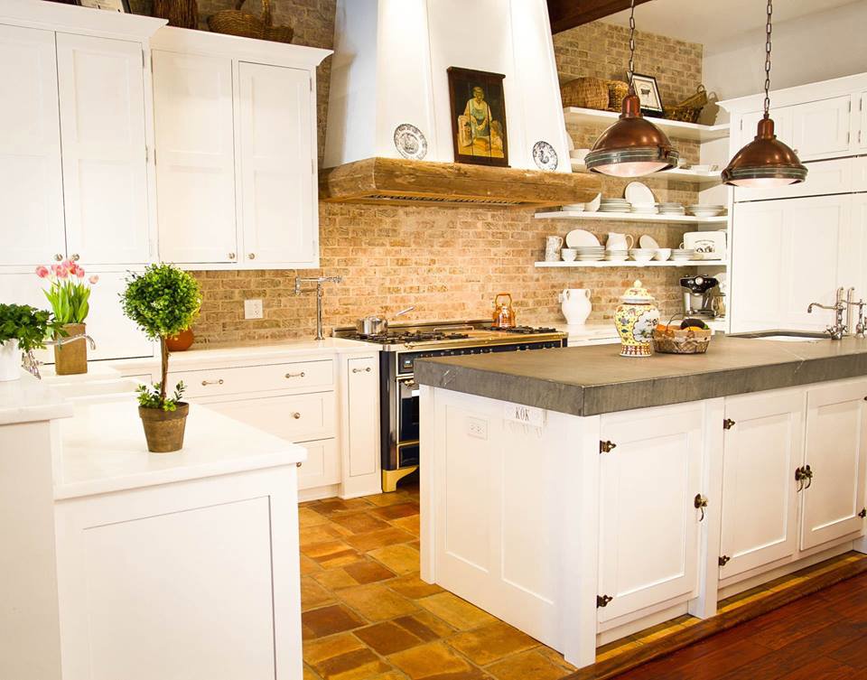 A kitchen renovation with white cabinets, a brick backsplash, a custom wooden range hood, and a large island by Surfaces By Design in Duluth, MN.