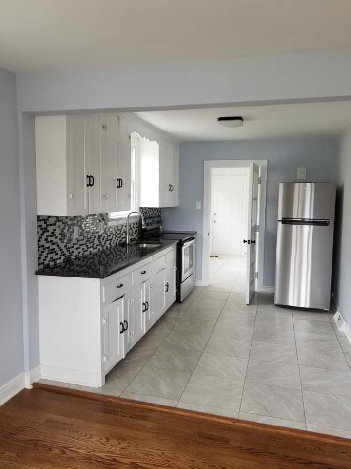 A modern kitchen renovation with white cabinets, black backsplash, and new appliances by Professional Contractor RVA in Richmond, VA.