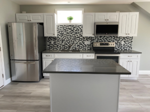 A newly renovated kitchen with modern appliances and mosaic backsplash by Casco Bay Construction Services, LLC in South Portland, ME.