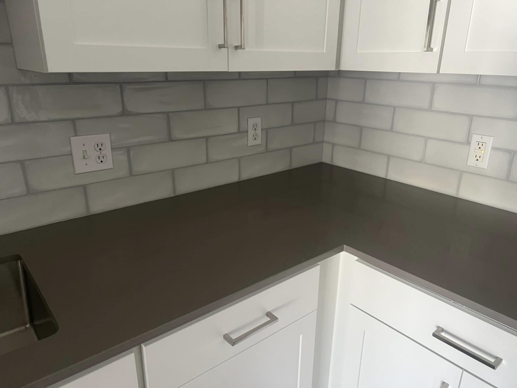 Corner view of a modern kitchen renovation featuring new cabinets, countertop, and backsplash by Fox Solutions Corp in Worcester, MA