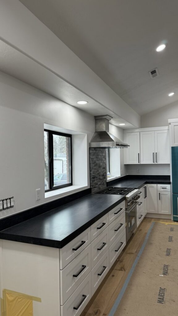 A kitchen undergoing renovation with new dark granite countertops and protective floor covering by Victor's Granite Counter-Tops in Millcreek, UT.