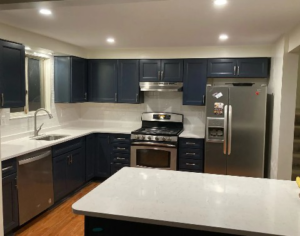 A modern kitchen renovation with dark blue cabinets, white countertops, and stainless steel appliances by McIntyre's Renovations LLC in Pittsburgh, PA