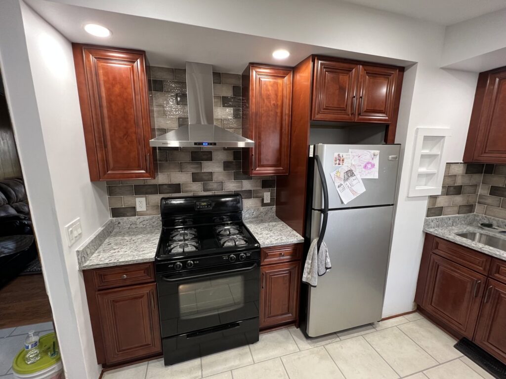 A kitchen renovation featuring dark wood cabinets, granite countertops, and a tiled backsplash by Amaro home improvement llc in Danbury, CT.