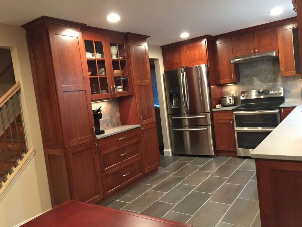 A stylish kitchen renovation with dark wood cabinets, stainless steel appliances, and tiled flooring by Mainville Construction & Remodeling LLC in Newington, CT.