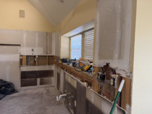 A kitchen undergoing demolition and renovation, showing exposed studs and plumbing, by AKN Design Group in Fort Worth, TX.