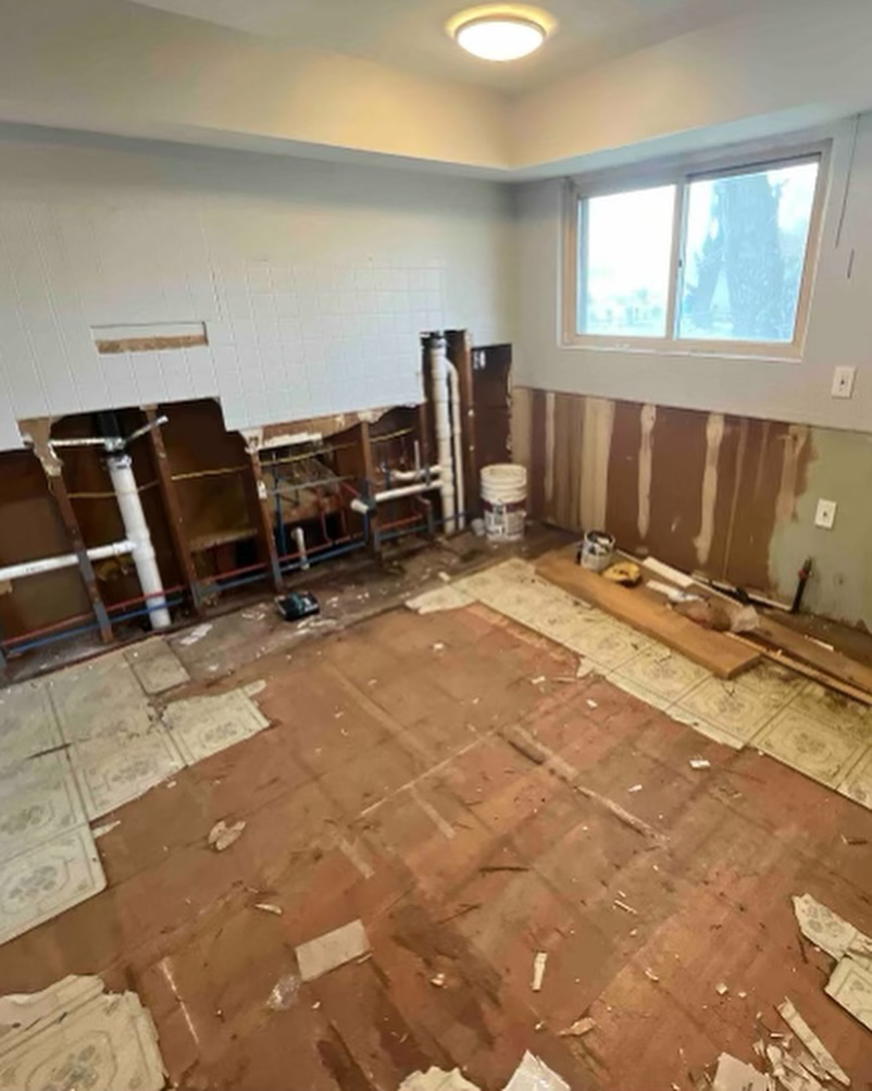 A kitchen undergoing demolition and renovation, showing exposed plumbing and removed flooring by Make It Happen Homes STL in St. Louis, MO.