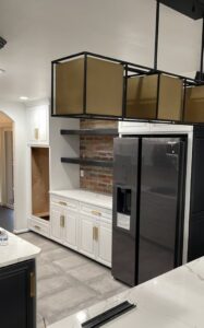 A kitchen renovation in progress, featuring new white cabinets, a refrigerator, and an exposed brick backsplash by Ruach Home Services in Laurel, MD.