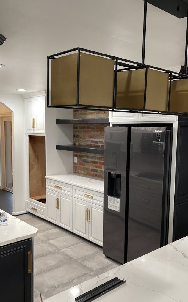 A kitchen renovation in progress, featuring new white cabinets, a refrigerator, and an exposed brick backsplash by Ruach Home Services in Laurel, MD.