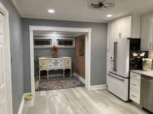 A newly renovated kitchen with white cabinets, granite countertops, and new flooring by Shore Home Construction Roofing in Salisbury, MD.