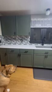 A renovated kitchen with stylish green cabinets, new countertops, and a tiled backsplash by Prime Construction And Flooring in Lorain, OH.
