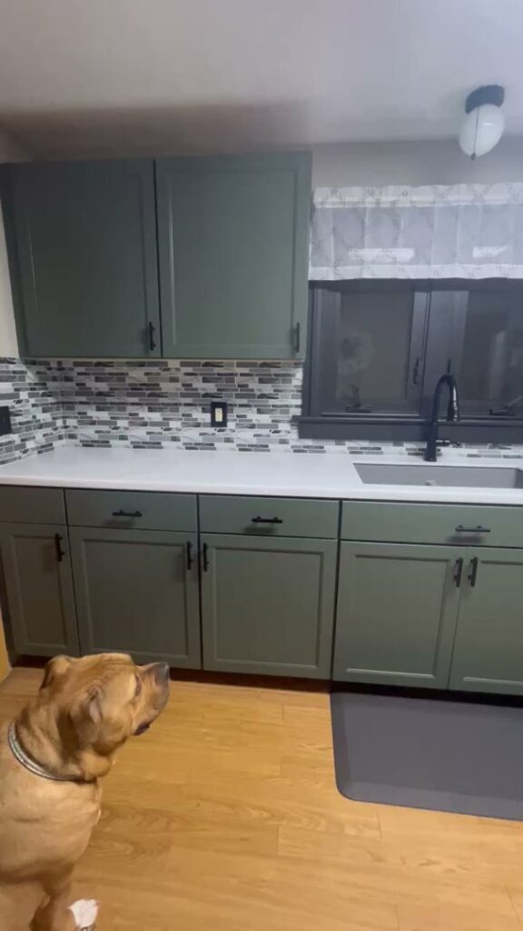 A renovated kitchen with stylish green cabinets, new countertops, and a tiled backsplash by Prime Construction And Flooring in Lorain, OH.