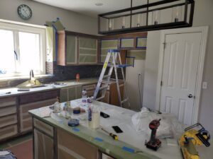 A kitchen undergoing renovation with cabinets taped and tools on the island by Affordable Granite of KC in Kansas City, MO.