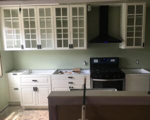 A kitchen renovation in progress showing newly installed white cabinets and range hood by Garrett Group Construction in Philadelphia, PA.