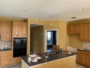 A kitchen renovation in progress, showing removed cabinets and walls prepped for painting by Brewer Builds in Fort Worth, TX.