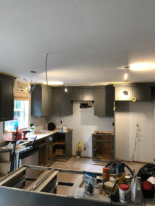A kitchen renovation in progress with new gray cabinets and exposed wiring by Caldwell Construction in Richardson, TX