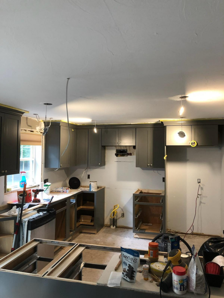 A kitchen renovation in progress with new gray cabinets and exposed wiring by Caldwell Construction in Richardson, TX