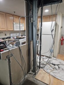 A kitchen undergoing renovation with exposed wiring and studs, handled by Paramount Development in Milwaukee, WI.