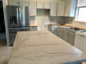 A kitchen renovation in progress, showcasing new grey cabinets and a modern island countertop installed by Stormtroopers Home Improvement in Port St. Lucie, FL.