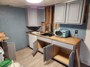 A kitchen renovation project in progress showing new cabinets and exposed wall studs by WHE Construction in Virginia Beach, VA