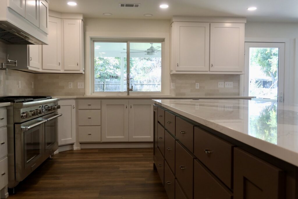 A spacious kitchen renovation showcasing a large island and white cabinets by Holaway Custom Builds in Fayetteville, AR.