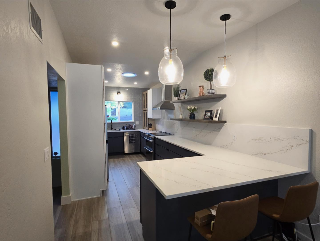 A spacious kitchen renovation with a new island, pendant lighting, and modern finishes by Raven Construction LLC in Tucson, AZ.