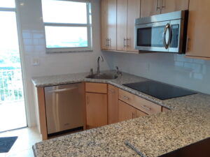 A completed kitchen renovation featuring light wood cabinets and granite countertops by Corley Construction Inc in Fort Lauderdale, FL