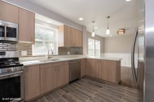 A modern kitchen renovation with light wood cabinets, stainless steel appliances, and pendant lighting by Grizzly Renovations in Naperville, IL
