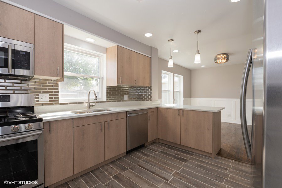 A modern kitchen renovation with light wood cabinets, stainless steel appliances, and pendant lighting by Grizzly Renovations in Naperville, IL