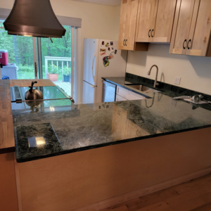 A newly renovated kitchen featuring dark green granite countertops and light wood cabinets by Jonny Hinton - Handyman Extraordinaire in Colorado Springs, CO.